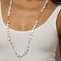 Pearl necklace worn by a person in a white top