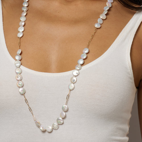 Pearl necklace worn by a person in a white top