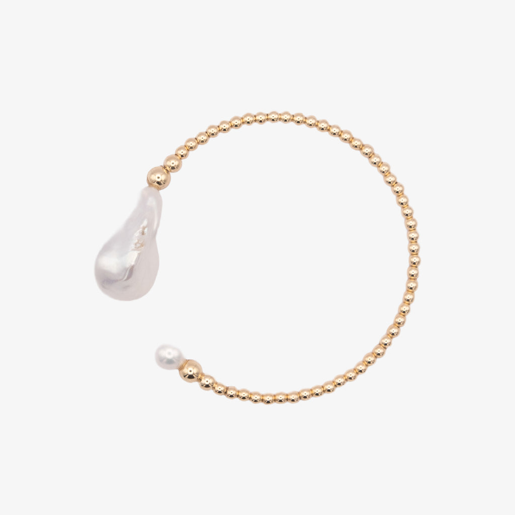 Gold bracelet with a teardrop-shaped pearl on a white background